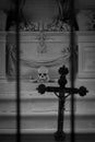 Skeleton head and bones beyond bars with a religious cross as sign of death and grave