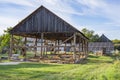 The skeleton of an old, destroyed barn being demolished on a sunny day. Grass