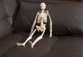 Skeleton sitting on the brown leather sofa