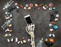 Skeleton using smartphone and halloween flat lay