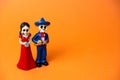 skeletons of a man and a woman for day of the dead festival in Mexico on a vibrant orange background, copy space