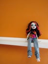 Monster Tall doll sitting on white shelf against orange painted wall