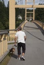 Skelleftea, Norrland Sweden - August 18, 2020: elderly man walking his dog over a wooden bridge Royalty Free Stock Photo