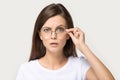 Skeptic millennial brunette woman lower glasses as sign of confusion