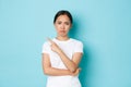 Skeptical and disapleased, grimacing asian girl looking disappointed or dissatisfied with promo offer, pointing finger Royalty Free Stock Photo