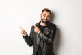 Skeptical and disapleased man in leather jacket, pointing fingers at upper left corner, showing bad promo offer Royalty Free Stock Photo