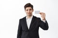 Skeptical, displeased male entrepreneur, business man shows credit card and frowning upset, dislike bank, standing over Royalty Free Stock Photo