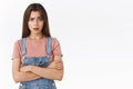 Skeptical shocked brunette woman in dungarees, t-shirt, cross hands over chest look with judgement and dismay, raise one
