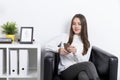 Skeptical woman in casual in armchair with mobile Royalty Free Stock Photo