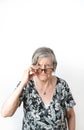 Skeptical woman looking at camera while peering over her eye glasses. White isolated background Royalty Free Stock Photo