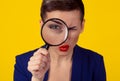 Skeptical woman looking through magnifying glass isolated yellow wall background. Funny woman skepticism concept. Positive human