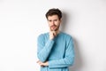 Skeptical young man frowning, looking with worried thoughtful look, standing upset over white background Royalty Free Stock Photo