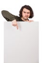Skeptical young man pointing forefinger to a blank banner for advertising and messages. Empty sheet, copy space for text Royalty Free Stock Photo