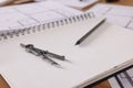 Sketchbook with construction drawings, pair of compasses and pencil on wooden table, closeup