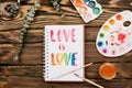 sketchbook with handlettering inscription `Love is love` on wooden table