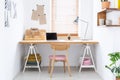 Sketchbooks and an open laptop on a wooden desk in a white, home office interior of a fashion designer. Real photo. Royalty Free Stock Photo