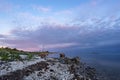 Evening sunlight on coast, pink clouds, blue sky reflection on water. Beach in summer. Seaside natural environment. Royalty Free Stock Photo