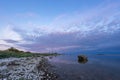 Evening sunlight on coast, pink clouds, blue sky reflection on water. Beach in summer. Seaside natural environment. Royalty Free Stock Photo