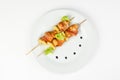 Skewers of chicken and pineapple with bacon on a round white plate on white isolated background Royalty Free Stock Photo