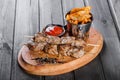 Skewers of Meat with sauce and potatoes fries in a bucket on wooden cutting board. Royalty Free Stock Photo