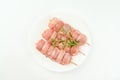 Skewers from raw chicken leg meat without skin on a white plate with fresh herbs rosemary for supermarket on a white Royalty Free Stock Photo