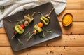 Skewers with tasty grilled vegetables and sauce on wooden table Royalty Free Stock Photo