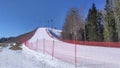 At the ski center, the slopes for safety are fenced with a mesh fence with metal poles, behind which there are trees. Snow melts i