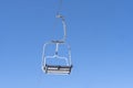 Ski chair lift over blue sky. Ski lift empty ropeway on hilghland mountain winter. Ski chairlift cable way with people enjoy Royalty Free Stock Photo