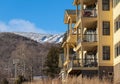 Ski condos with forest and snowy mountain in the background against blue sky on a sunny day