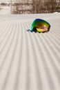 Ski goggles laying on a new groomed snow and empty ski slope