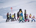 Ski instructor in a penguin suit studies children in ski school.