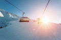 Ski lift empty ropeway on hilghland alpine mountain winter resort on bright sunny evening . Ski chairlift cable way with people Royalty Free Stock Photo