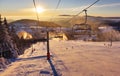 Ski lift empty ropeway on hilghland alpine mountain winter resort on bright sunny evening . Ski chairlift cable way with people Royalty Free Stock Photo