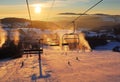 Ski lift empty ropeway on hilghland alpine mountain winter resort on bright sunny evening . Ski chairlift cable way with people Royalty Free Stock Photo