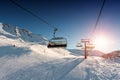 Ski lift empty ropeway on hilghland alpine mountain winter resort on bright sunny evening . Ski chairlift cable way with Royalty Free Stock Photo