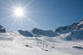 Ski lift at high altitude resort, sun with flare Royalty Free Stock Photo