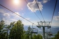 Ski lift in the mountains on sunny day against blue sky, white clouds, green hills and mountain lake. Mountain valley with cable Royalty Free Stock Photo