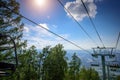 Ski lift in the mountains on sunny day against blue sky, white clouds, green hills and mountain lake. Mountain valley with cable Royalty Free Stock Photo