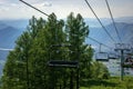 Ski lift in the mountains on sunny day against blue sky, white clouds, green hills and mountain lake. Mountain valley with cable Royalty Free Stock Photo