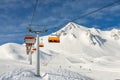 Ski lift ropeway on hilghland alpine mountain winter resort on bright sunny day. Ski chairlift cable way with people enjoy skiing