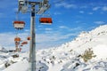 Ski lift ropeway on hilghland alpine mountain winter resort on bright sunny day. Ski chairlift cable way with people enjoy skiing