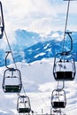 Ski lift with skiers above the slope of snowy Alpine mountains Royalty Free Stock Photo