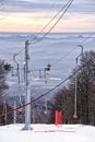 Ski lift on the snow covered hill above the cloudy panaroma of hills Royalty Free Stock Photo