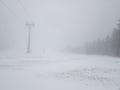 Ski lift in white thick fog. End of winter season with melting snow