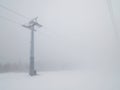 Ski lift in white thick fog. End of winter season with melting snow