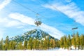 Ski Lifts Carrying Skiers Over Pine Trees Against Blue Sky