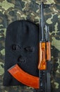 Ski mask and ak 47 on a camouflage background