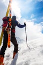 Ski mountaineer walking up along a steep snowy ridge with the s