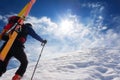 Ski mountaineer walking up along a steep snowy ridge with the s