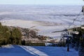 Ski slope from the top with hills and cloud covered panorama